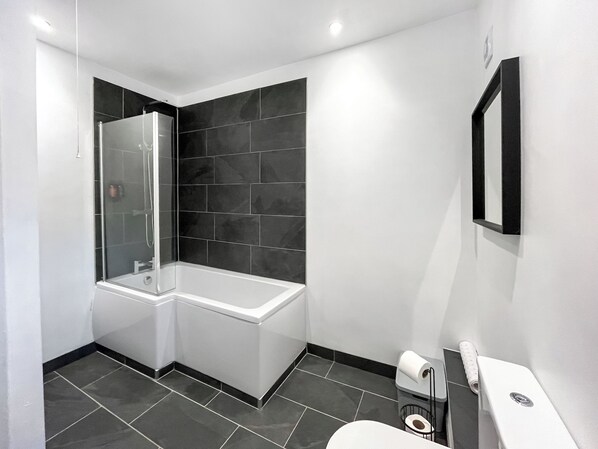 A modern bathroom with a glass-enclosed shower, a white bathtub, and a toilet. - 3 bedroom accommodation in Colwyn Bay (Colwyn Bay)