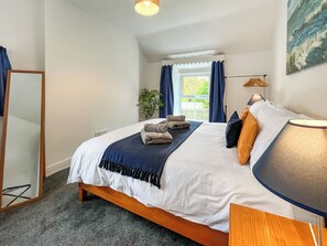 A neatly made bed with towels, a bedside lamp, and a view of the outdoors through a window. - 3 bedroom accommodation in Colwyn Bay (Colwyn Bay)