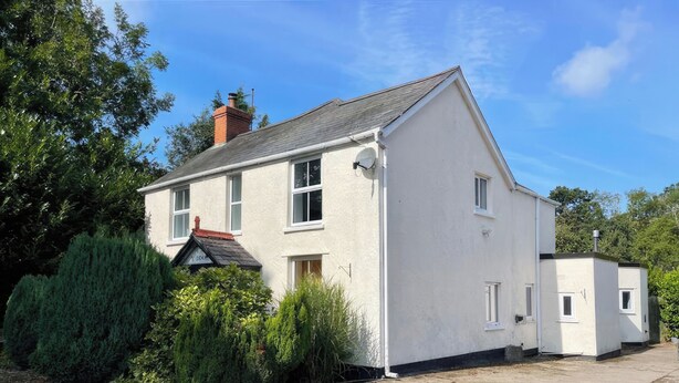 A two-story house with a gravel driveway, surrounded by greenery. - 3 bedroom accommodation in Colwyn Bay (Colwyn Bay)