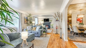 Un salon moderne avec un canapé, une table basse et une cheminée. On y trouve également un coin repas avec des chaises et une table.