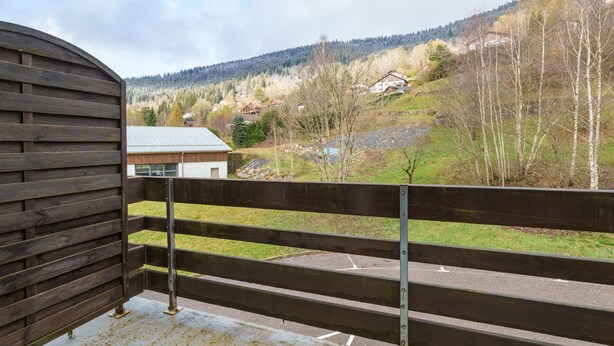 A balcony with a view of a rural landscape, including houses and trees.