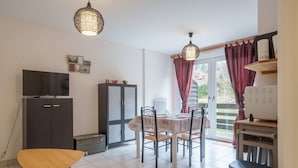 A compact kitchen with a dining table, chairs, a TV, and a refrigerator.