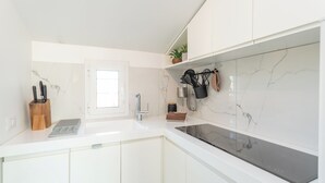 Eine moderne Küche mit weißen Schränken, einer Marmor-Spritzschutzwand und einem eingebauten Herd.