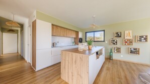 Eine moderne Küche mit Holzausstattung, einer zentralen Kochinsel und einem Weinelement an der Wand.