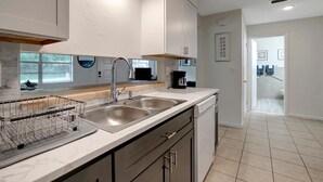 A modern kitchen with a double sink, a coffee maker, and a dish rack.