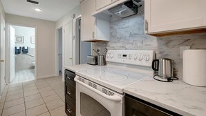 A modern kitchen with a built-in oven, a stovetop with four burners, a coffee maker, and a microwave.
