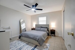 A bedroom with a bed, bedside tables, a ceiling fan, a mirror, and a window. - Tranquil 2-bedroom apartment in Crystal River with WiFi, AC (Crystal River)