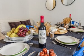 A dining table set with plates, a bottle of wine, and a fruit bowl.