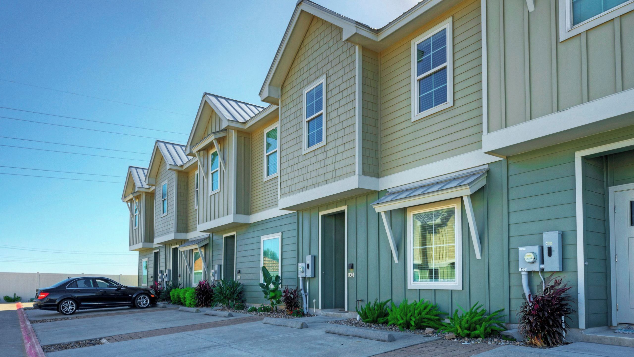 A row of townhouses with a garage, a driveway, and a car parked on the street.