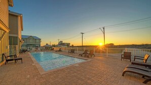 A swimming pool with lounge chairs, a brick patio, and a sunset view. - Ridley Retreat Community Pool, Mins to the Beach Corpus Christi + Port A (Corpus Christi)