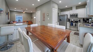 A modern kitchen with white cabinets, a wooden dining table, and a built-in oven. - Ridley Retreat Community Pool, Mins to the Beach Corpus Christi + Port A (Corpus Christi)