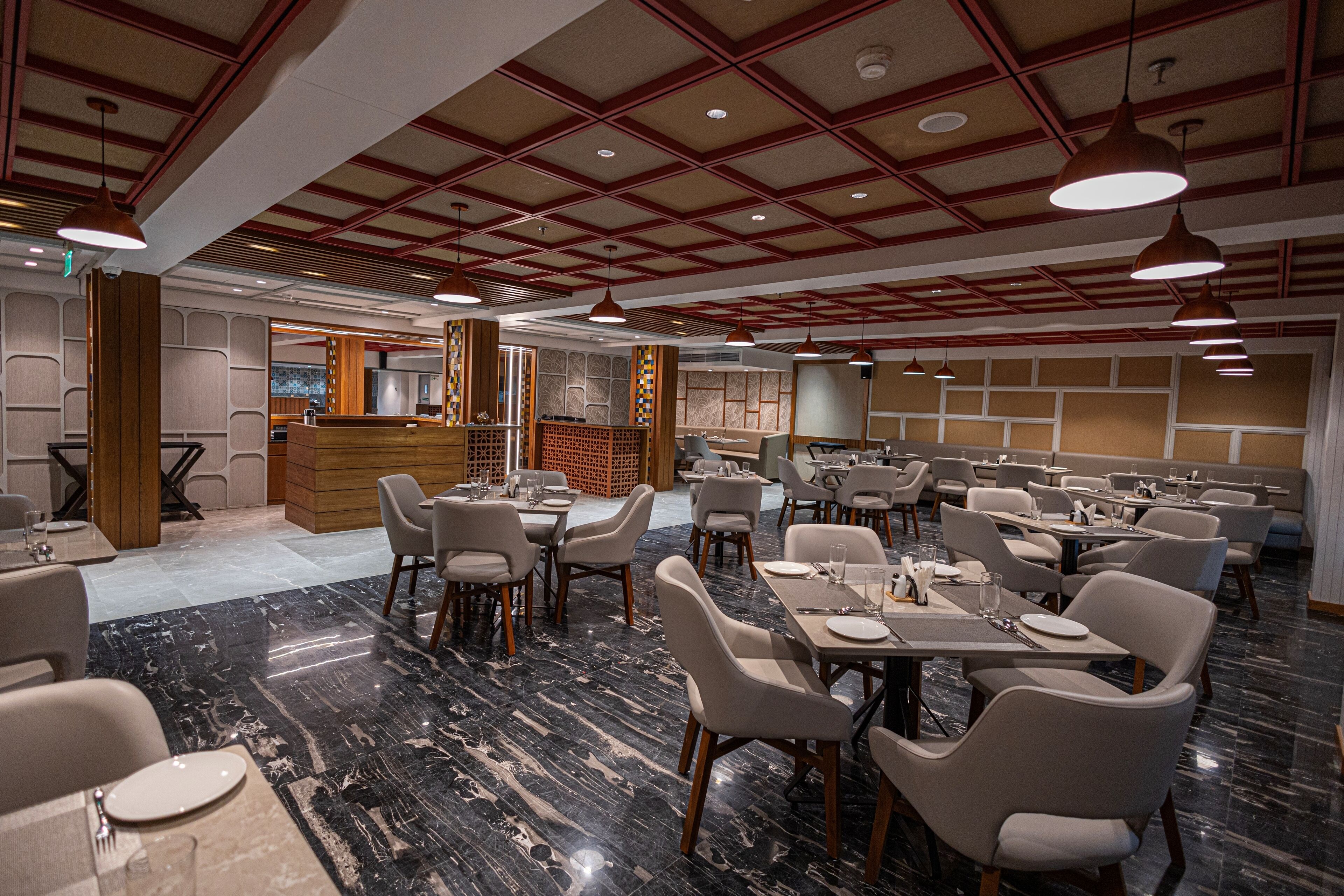 A spacious restaurant with high ceilings, marble flooring, and modern lighting fixtures.