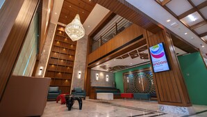 A modern lobby with a chandelier, seating areas, and a large digital screen displaying 'RAMADA ENCORE'. - Ramada Encore By Wyndham Viramgam (Viramgam)