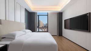 A modern hotel room with a large bed, a flat-screen TV mounted on the wall, and a view of the city through a large window. - Days Hotel By Wyndham Xianju Downtown (Taizhou)