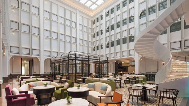 A spacious lobby with a high ceiling, a central seating area with sofas and round tables, and a distinctive spiral staircase. - Days Hotel By Wyndham Xianju Downtown (Taizhou)