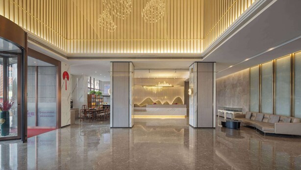 Eine moderne Hotelhalle mit einer Rezeption, einer Sitzecke und einer großen Kandelaber.