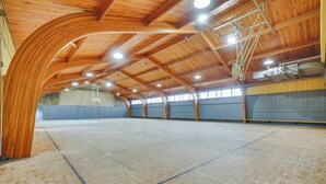 Una palestra al coperto con soffitto e pareti in legno, un campo da basket e condotti di ventilazione a vista.