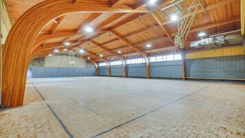 Une salle de sport intérieure dotée d’un plafond et de murs en bois, d’un terrain de basket-ball et de conduits de ventilation apparents.