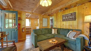 Ein Holzinterieur mit einem grünen Sofa, einem Holztisch und einem Willkommensschild.