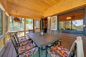 A wooden deck with a table and chairs, a hanging flower basket, and a view of the outdoors. - 'Knotty Kabin' Rustic Waterboro Cabin By Lake (Waterboro)