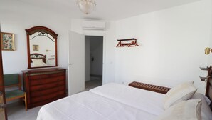 A bedroom with a bed, dresser, mirror, and a coat rack. - 1002 Casa Miramar (Nerja)