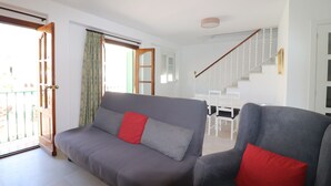 A living room with a grey sofa and armchair, a staircase, and a dining area. - 1002 Casa Miramar (Nerja)