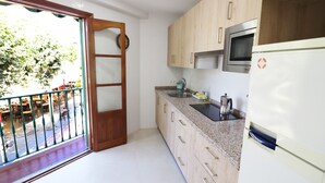 A kitchen with wooden cabinets, a stainless steel microwave, and a refrigerator. - 1002 Casa Miramar (Nerja)