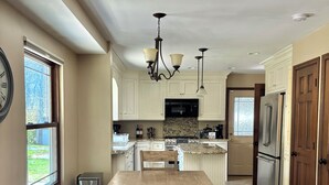 Una cocina amplia con una isla central, electrodomésticos integrados y un comedor con mesa de madera.
