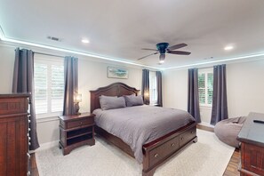 Cozy retreat with a large bed, nightstand, dresser, and ceiling fan.