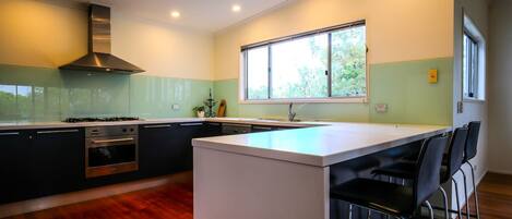 A modern kitchen with a central island, stainless steel appliances, and a large window providing natural light.