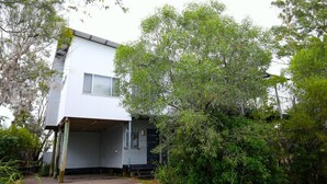 Ein zweistöckiges Haus mit einer Garagentür, umgeben von üppiger Vegetation und Bäumen.