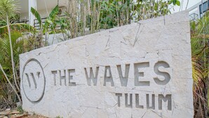 A stone sign with the text "THE WAVES TULUM". - Wellness Suite with Spa, Gym & Rooftop (Tulum)