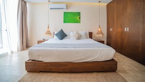 A modern bedroom with a large bed, wooden wardrobe, and a green abstract painting on the wall. - Wellness Suite with Spa, Gym & Rooftop (Tulum)