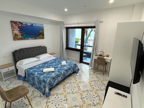 Une chambre d’hôtel équipée d’un lit, d’un bureau, d’une chaise, d’une télévision et d’une fenêtre donnant sur la mer.