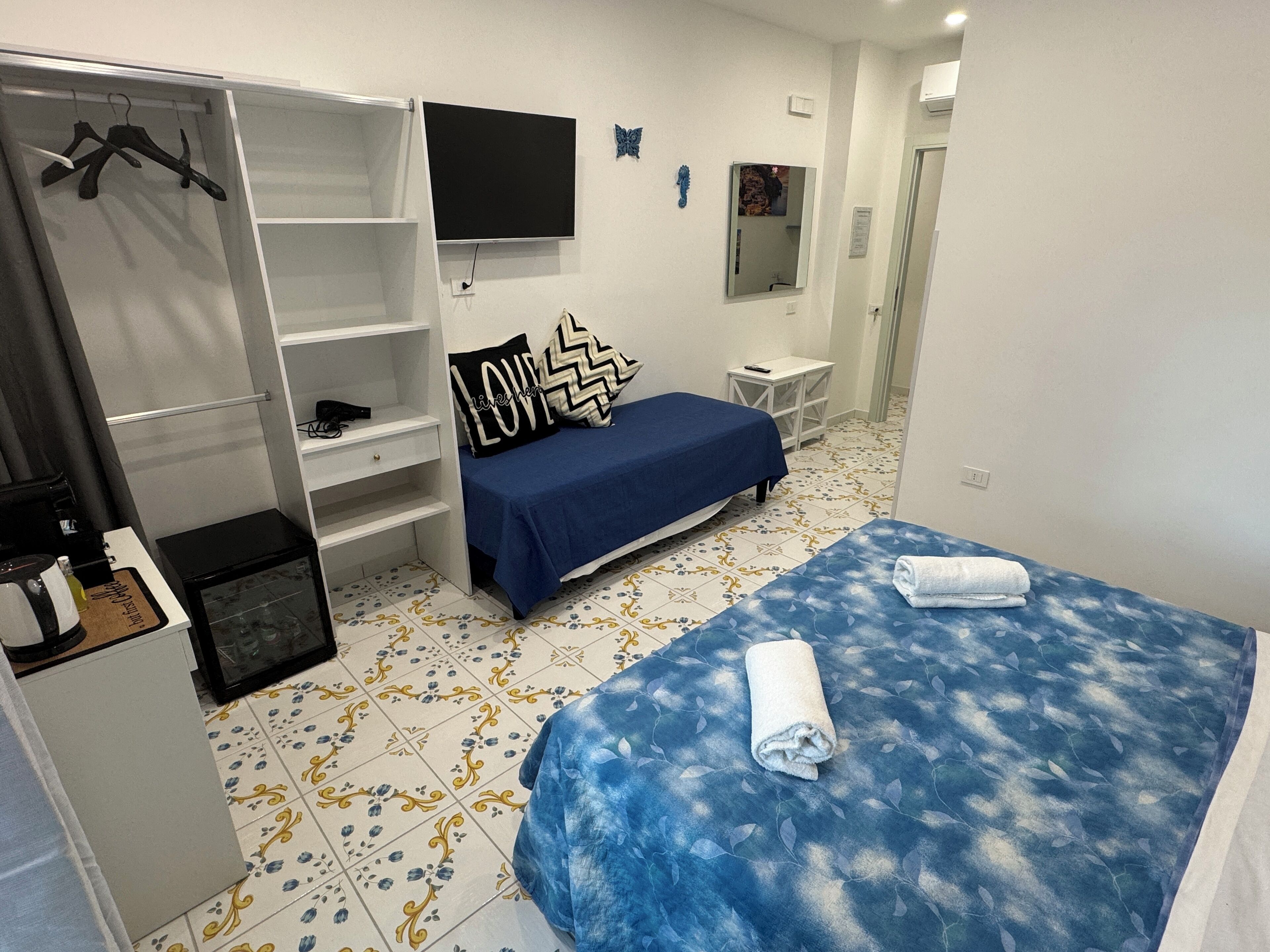 Un dormitorio con cama, televisor, armario y una mesita.