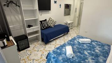Un dormitorio con cama, televisor, armario y una mesita.