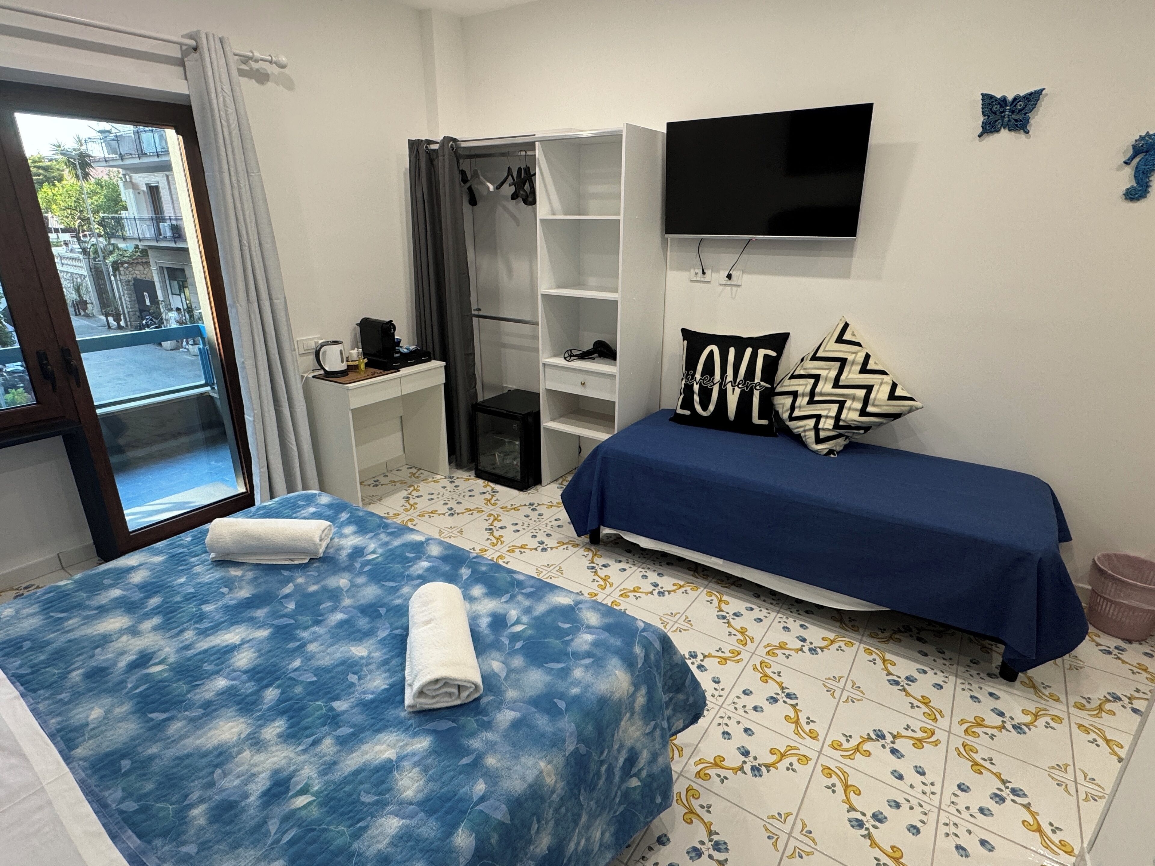 A bedroom with two beds, a TV, a wardrobe, and a desk.