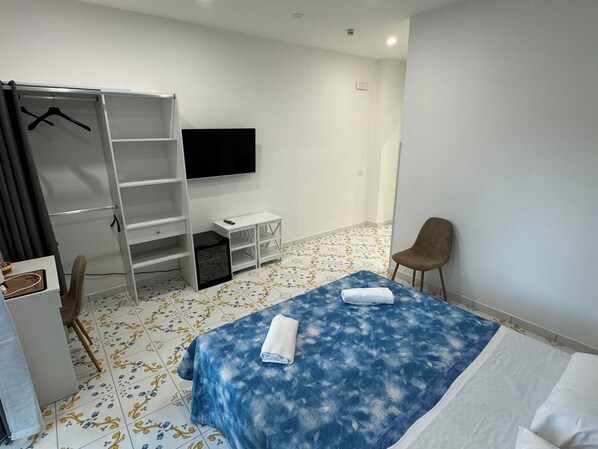 A hotel room with a bed, a TV, a wardrobe, a chair, and a small table. - Angela House Sorrento Center (Sorrento)