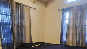 Ein Zimmer mit einem Bett, einem Nachttisch und Vorhängen.