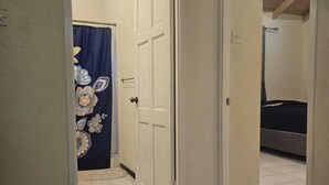 Ein Korridor mit Fliesenboden, einer Tür zu einem Schlafzimmer und einem Vorhang mit Blumenmuster.