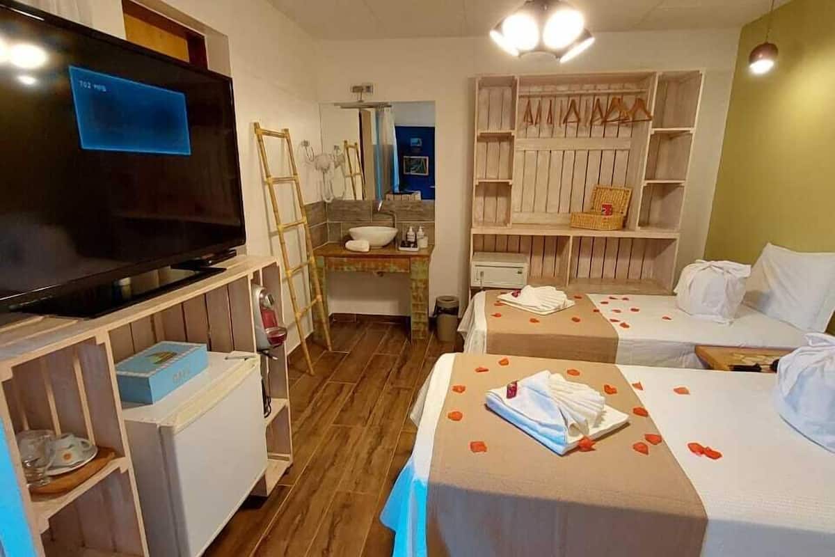 Une chambre d’hôtel équipée d’une télévision, d’étagères en bois, d’un bureau et de deux lits.