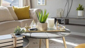 Un salon moderne avec un canapé, une table basse ronde agrémentée d’objets décoratifs et un téléviseur fixé au mur.