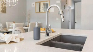 Une cuisine moderne avec un évier en acier inoxydable, un robinet et un flacon de savon liquide pour les mains.