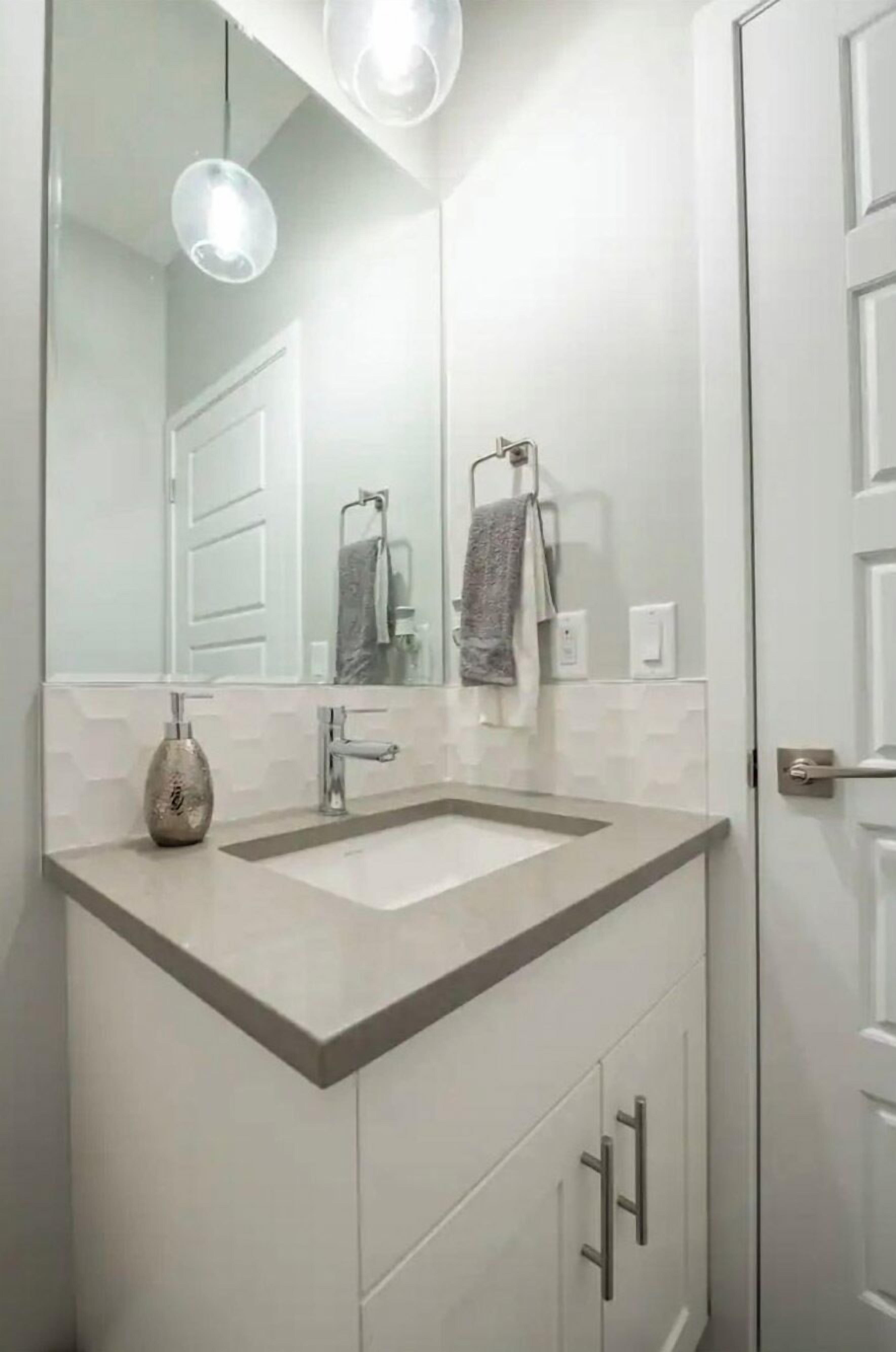 A modern bathroom with a large mirror, two sinks, and a towel rack.