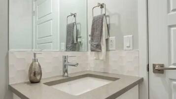 A modern bathroom with a large mirror, two sinks, and a towel rack.