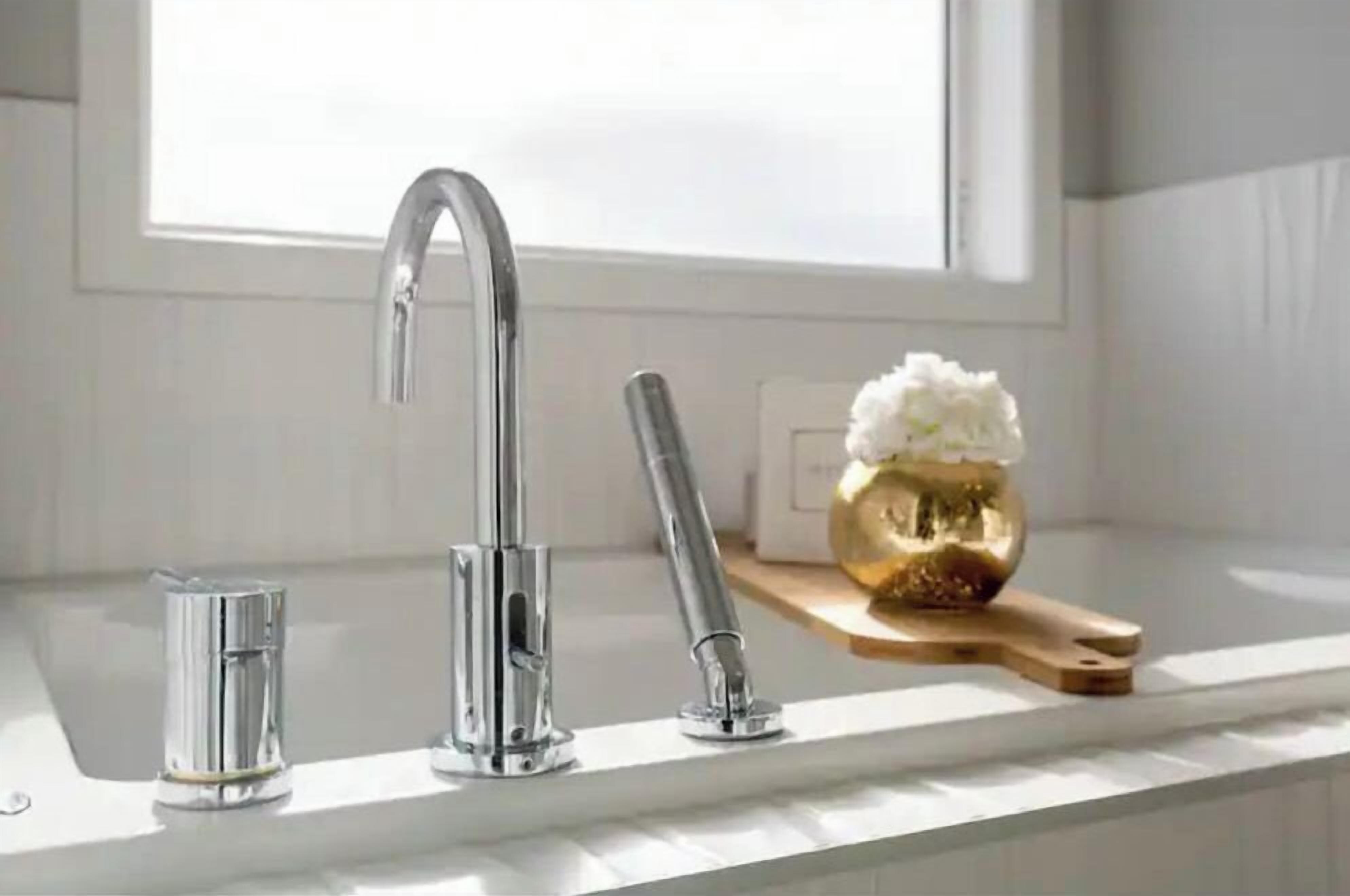 A modern kitchen with a stainless steel faucet, a small glass container, and a golden decorative item on the counter.