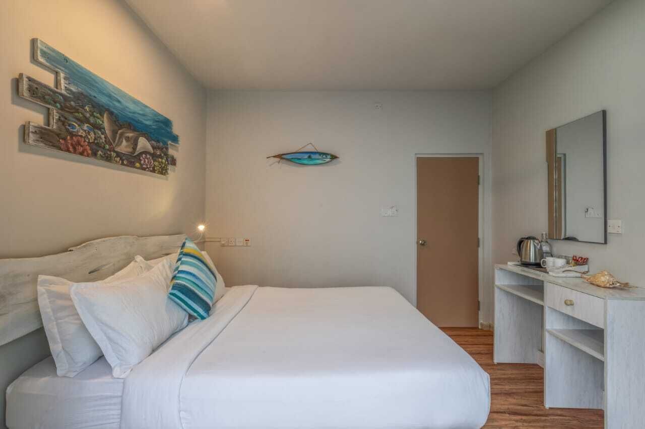 A bedroom with a bed, a dresser, a mirror, and wall art.