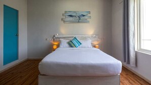 A bedroom with a bed, a painting on the wall, and a window with curtains. - AAN Beach View (Gulhi)