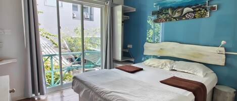 A bedroom with a bed, a ceiling fan, a window with curtains, and a view of greenery outside.