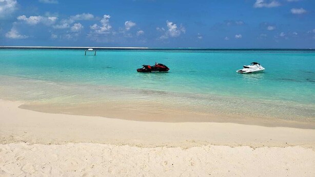 A beach with clear turquoise water, a sandy shore, and two boats. - AAN Beach View (Gulhi)